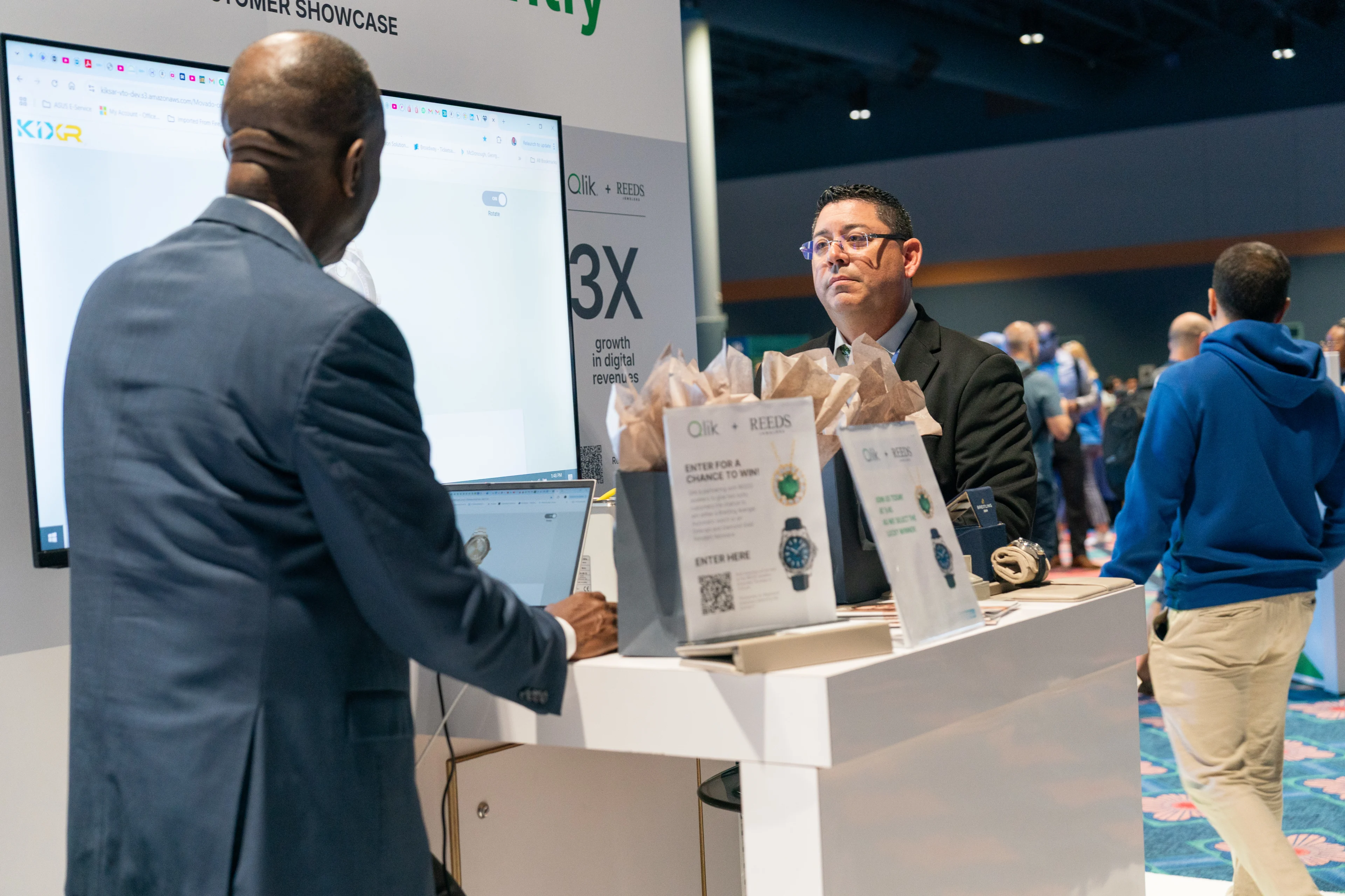 Attendees engage in a discussion at a Qlik and REEDS Jewelers booth during a Qlik Connect event, showcasing data-driven business growth and partnership success.