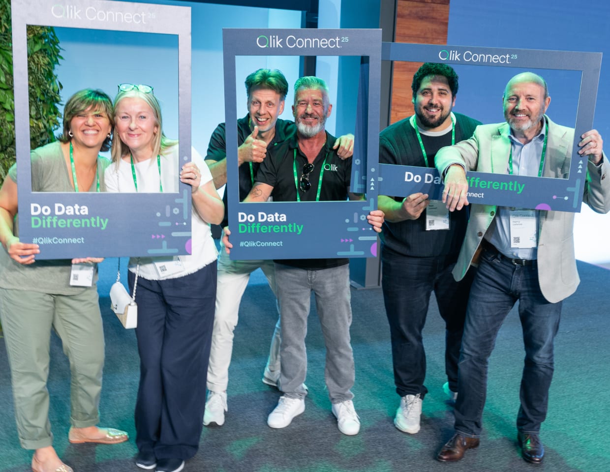 A group of smiling attendees at Qlik Connect 2025 pose with branded photo frames featuring the slogan “Do Data Differently,” celebrating community and collaboration at the event.