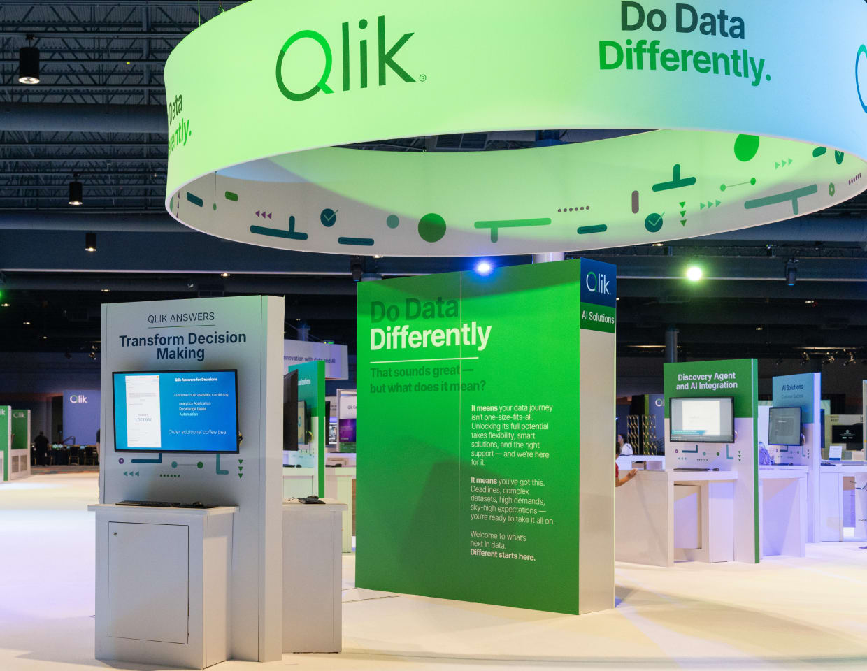 A vibrant Qlik exhibition booth showcasing the slogan “Do Data Differently.”