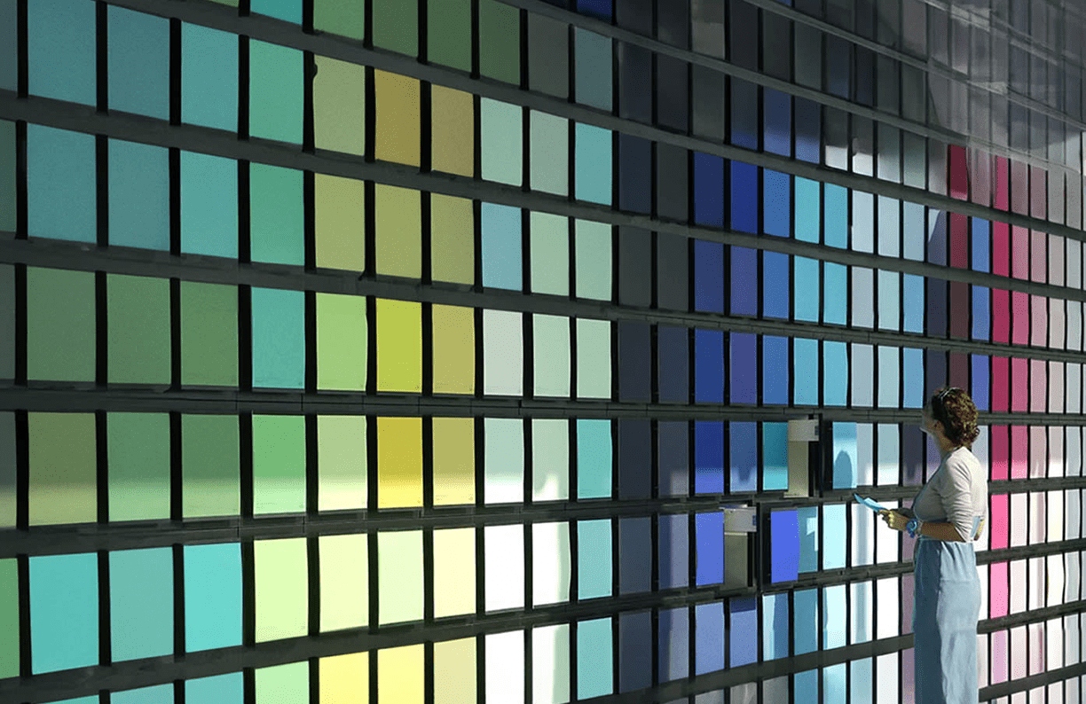 A person is positioned in front of a wall showcasing an array of color samples for design inspiration.