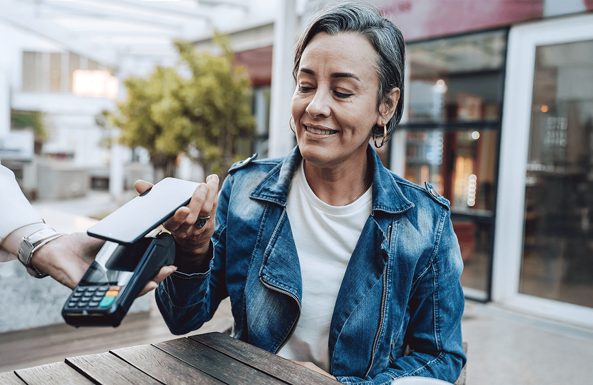 A woman using her phone to make a payment while shopping.