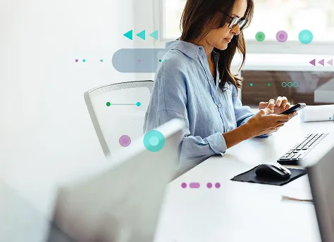 A woman working with her phone in front of a computer
