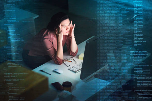 A woman sits at her desk with her head in her hands, conveying a sense of frustration or exhaustion.