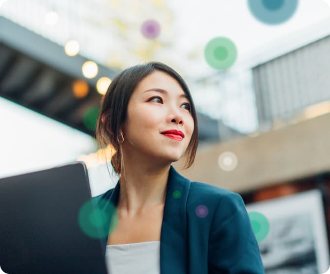 A confident woman working on a laptop with abstract bokeh elements floating around her