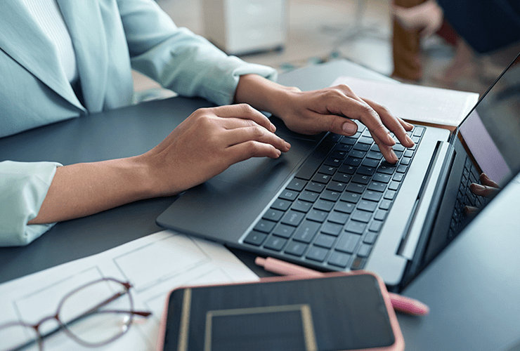 A person typing on their laptop, fingers on the keyboard.