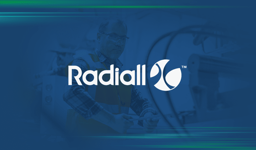 Radiall logo overlaying a blurred image of a man in an orange vest and safety goggles operates a machine.